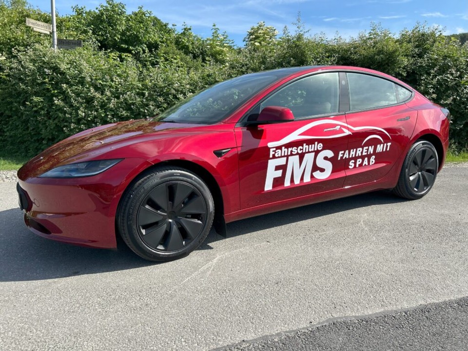 Das rote Tesla-Model-3-Schulfahrzeug der Fahrschule FMS mit FMS-Beschriftung