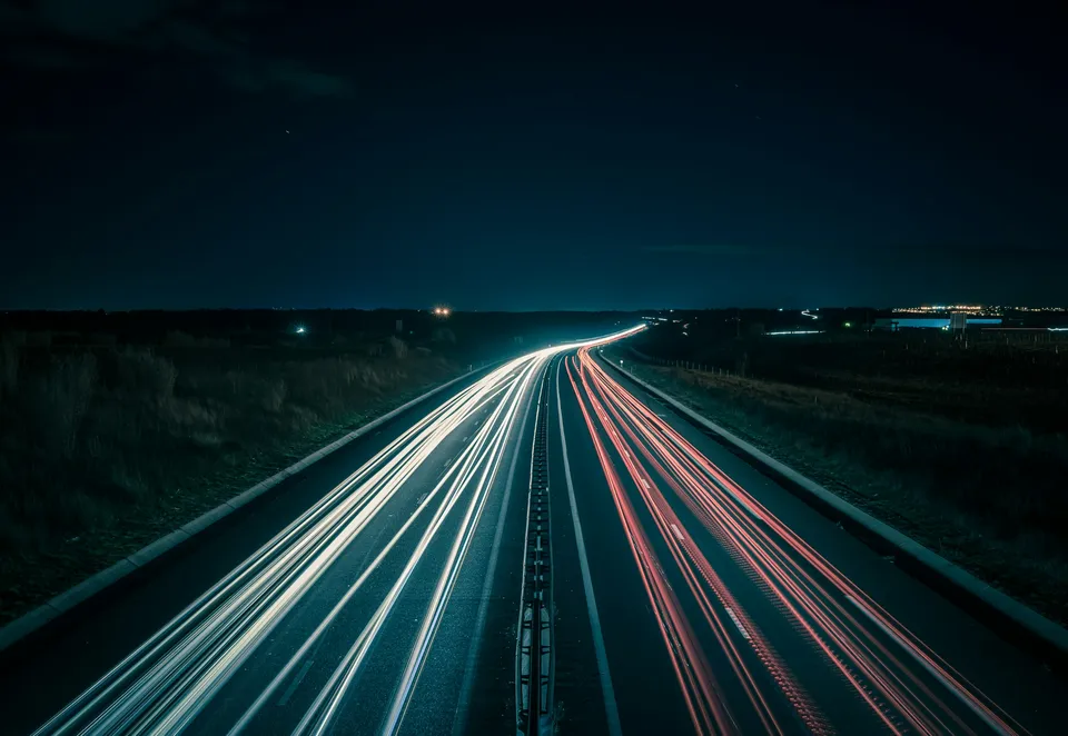 Straße bei Nacht mit Lichtspuren